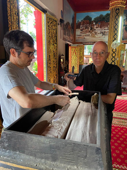 Gregory Kourilsky et David Wharton examinant une collection de manuscrits dans un monastère du nord de la Thaïlande.